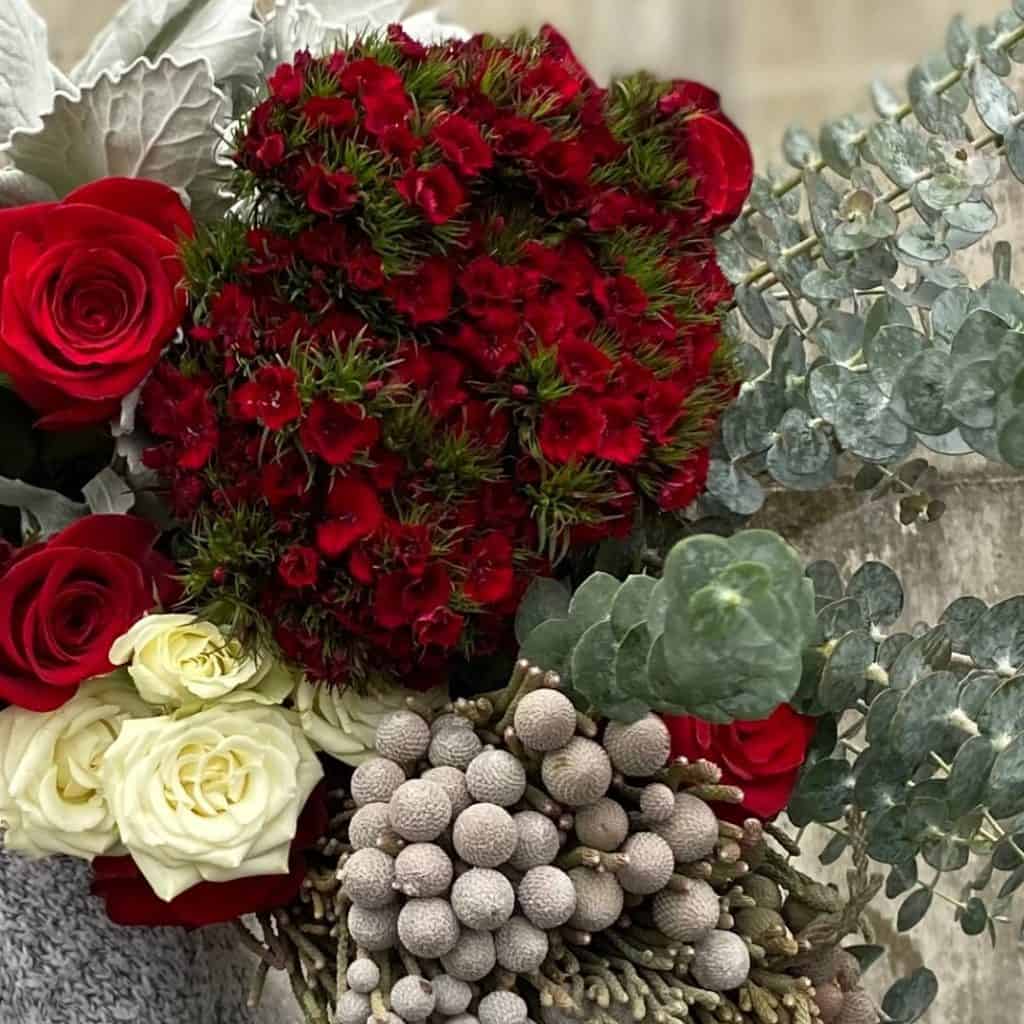 red flowers, red roses, mixed whole sale flowers and eucalyptus on a table