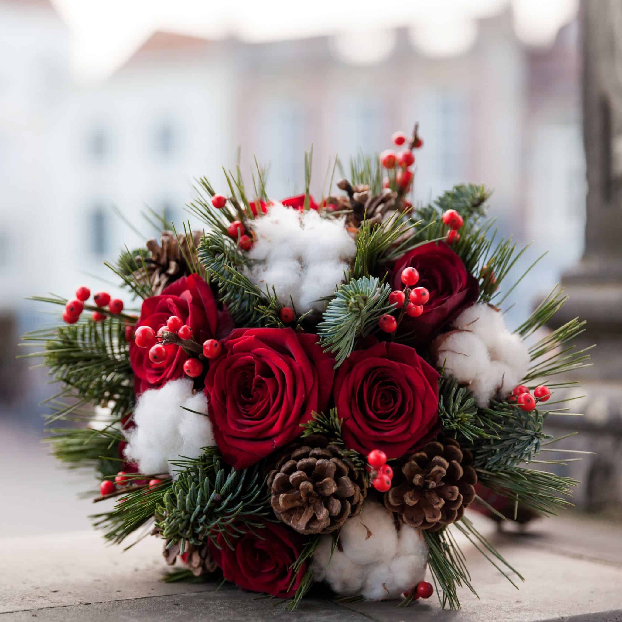 https://www.cascadefloralwholesale.com/wp-content/uploads/2021/11/Holiday-bouquet-with-pine-cones-red-roses-white-cotton-flowers-berries-and-green-pine-accents.jpg