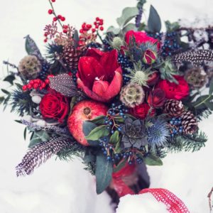 gorgous winter bouquet with scabiosa flowers blue thistle red roses pinecones and feathers