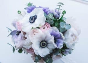 small wedding bouquet made up of white and lavender anemones and peach ranunuculs