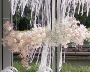 Beautiful blooming pink roses and baby's breath decorate the arch for the wedding ceremony. Luxury holiday decorations. Holiday traditions. Plastic chairs. Outdoors in the summer.