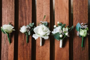 Top view of wedding boutonniere for the groom and bridesmaids on wooden background, free space. Wedding details outdoor with copy space. Wedding morning preparation