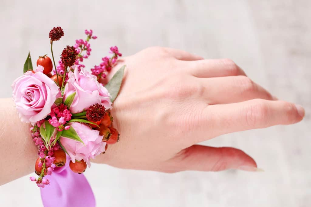 Florist at work: Steps of making wrist corsage for autumn wedding. Woman making beautiful bouquet of pink roses and heather.