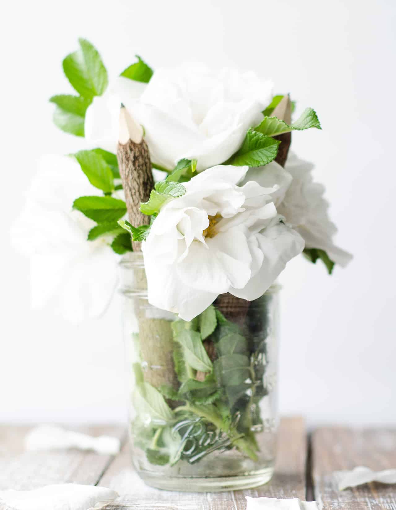 white gardenia flowers on wooden desk in mason jar