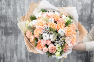 Beautiful luxury bouquet of winter flowers, round, fluffy, pink, peach, white, and silver.