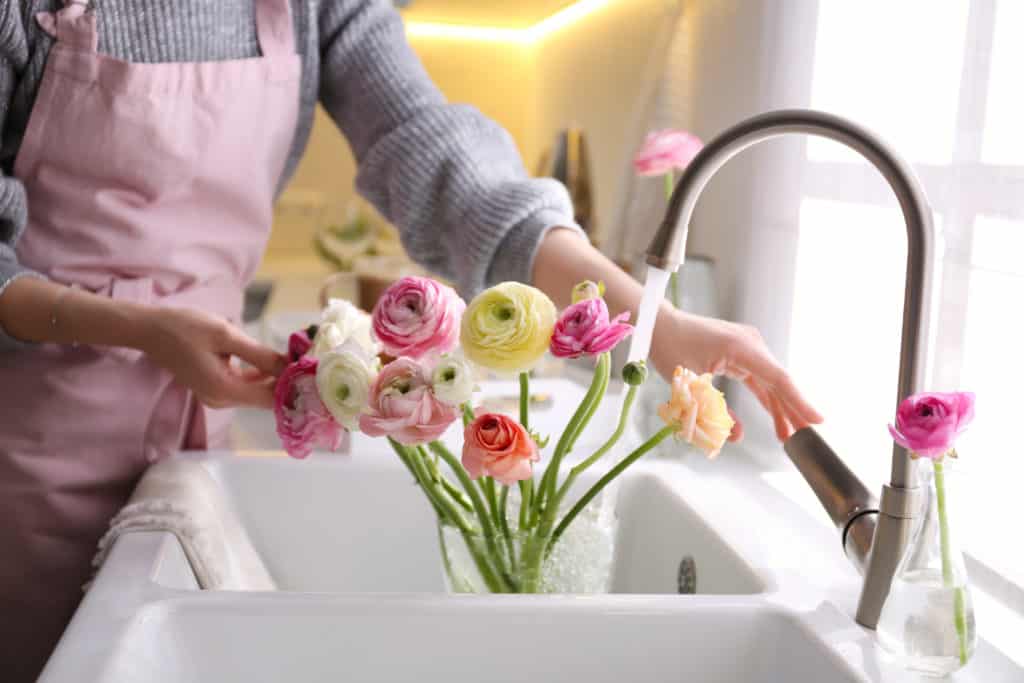 Woman placing water in vase of ranunculus