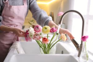 Woman placing water in vase of ranunculus
