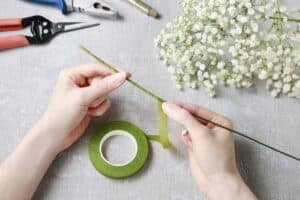Hands wrapping floral tape on wire