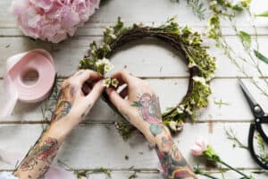 Tattooes hands adding flowers to crown