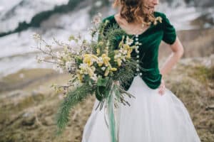 Women in green and white dress holding winter bouquet