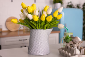 Yellow and white tulips in white container in kitchen