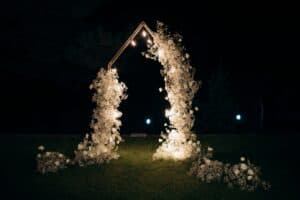 Lit up white floral arch at night