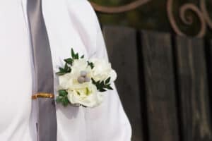 White and green boutonniere on silver suspender