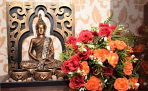 Red and orange rose bouquet by Buddha statue