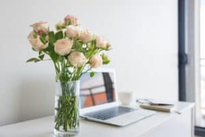 Vase of roses on desk with laptop
