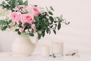 Pink roses in white vase with candles