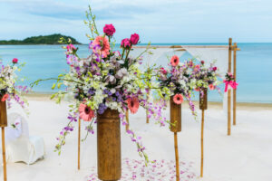 Large tropical arrangements marking aisle on beach