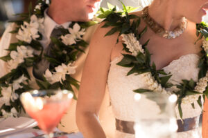 Bridge and groom wearing matching orchid leis