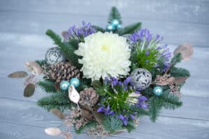 Holiday centerpiece with white flower, pinecones, and greenery