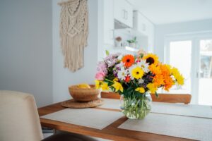 Bouquet of colorful flowers on dining table near macrame