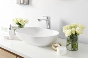 White roses in two vases by sink