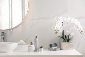 While orchid plant in white marble bathroom