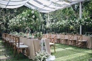 Outdoor wedding venue with white florals and abundant greenery under tent