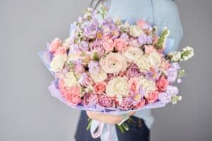 Woman holding wrapped floral bouquet with ranunculus
