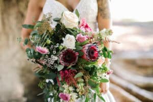 Bride with tattoo holding cascading bouquet with protea
