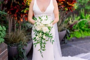 Bride holding white cascading bouquet with greenery