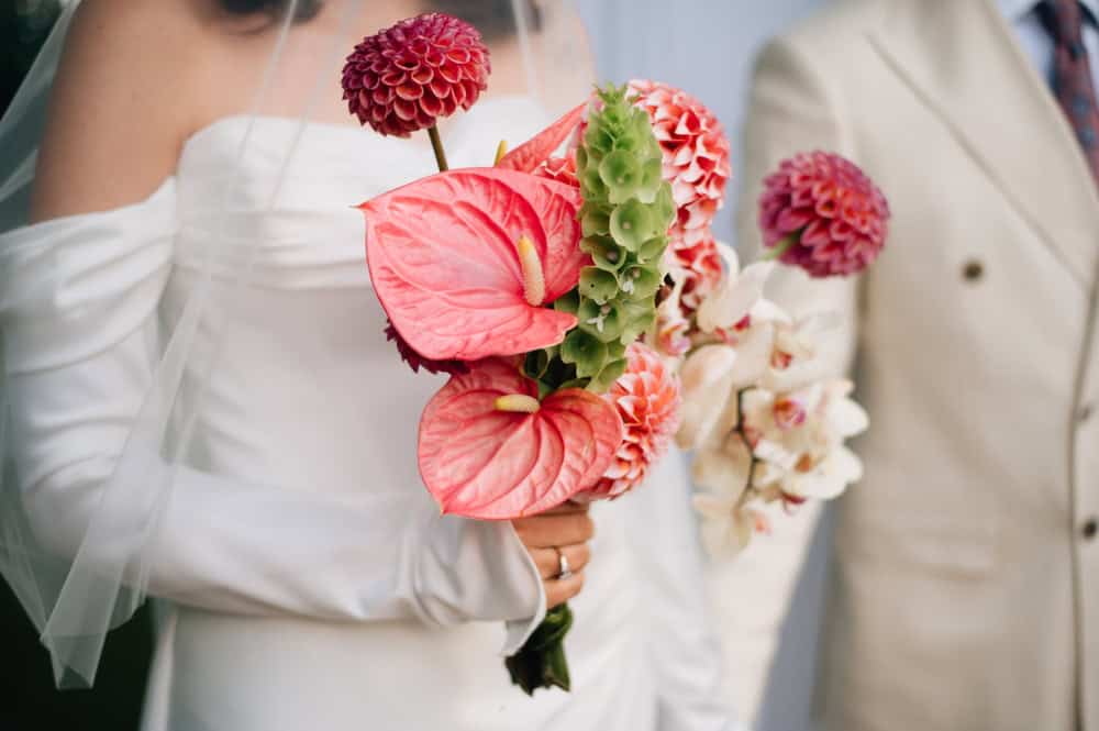 Bride carrying sculptural bouquet with anthurium and dahlia